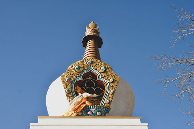 Low angle view of statue against temple building against clear sky