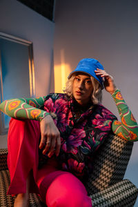 Confident blonde woman wearing trendy clothes sitting at studio and looking at the camera.