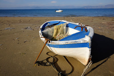 Boat moored on beach against sky