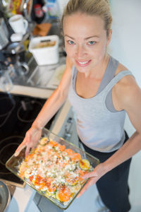 High angle portrait of smiling woman preparing food at kitchen