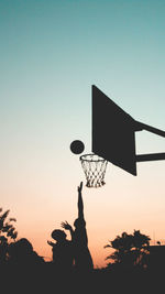 Low angle view of basketball hoop against sky during sunset