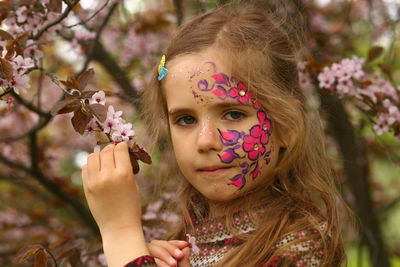 Spring portrait of a six year old girl standing under the blooming pink cherry tree