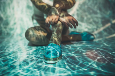 Low section of person wearing shoes on swimming pool