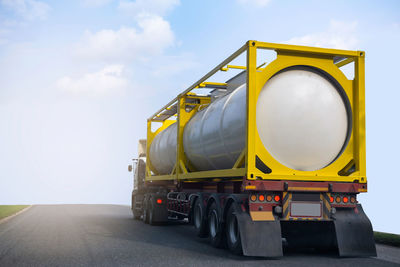 Yellow container on road against sky