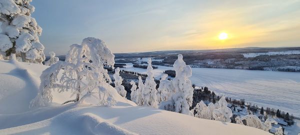 Panoramic view of snow covered landscape against sky during sunset