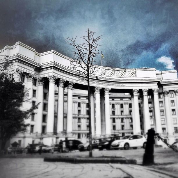 building exterior, architecture, built structure, sky, city, cloud - sky, cloudy, street, facade, building, incidental people, city life, cloud, tree, low angle view, outdoors, weather, street light, person, travel destinations