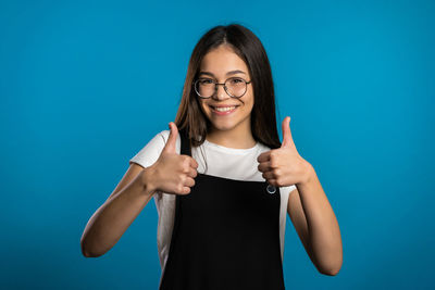 Portrait of a smiling young woman against blue background