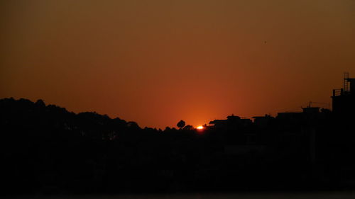 Silhouette trees against clear sky during sunset