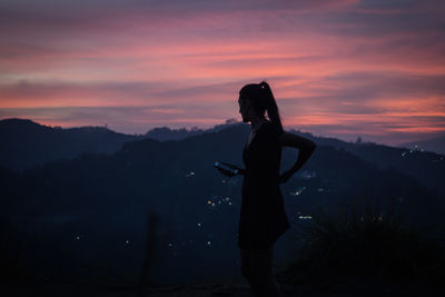 Silhouette woman standing in mountains against sky during sunset