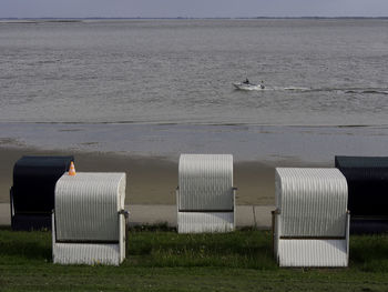 Hooded chairs on beach against sky