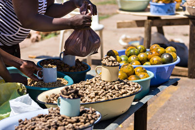 Midsection of woman buying nuts at market on sunny day