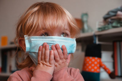 Close-up of cute girl wearing mask at home