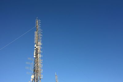 Low angle view of communications tower against blue sky