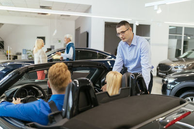 Salesman advising customers in car dealership