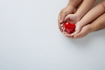 Close-up of hand holding ring over white background