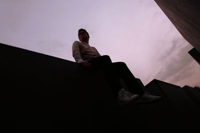 Low angle view of woman sitting against sky