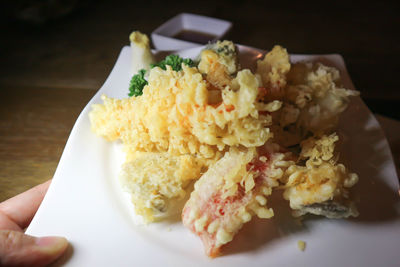 Close-up of hand holding food in plate