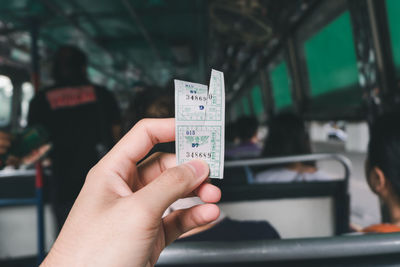 Cropped hand holding ticket in bus