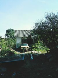 Abandoned house by trees against clear sky