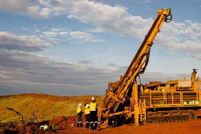 People working at construction site against sky