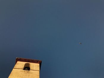 Low angle view of bird flying against clear blue sky