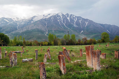 Wooden fence on field by mountains against sky