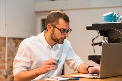 Young man using mobile phone while sitting on table