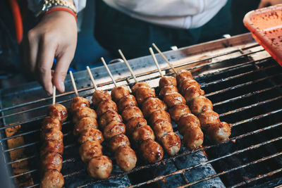 Close-up of man preparing food on barbecue grill