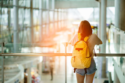 Rear view of woman with backpack standing by railing