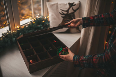 Midsection of woman opening wooden box by christmas decoration