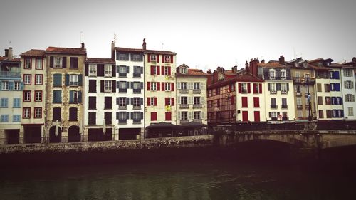 Residential buildings by river against clear sky