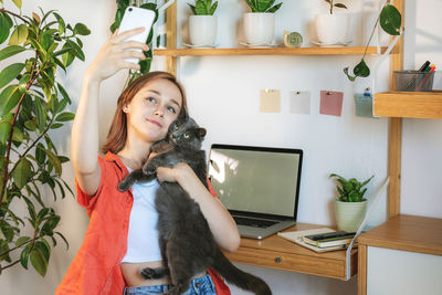 Young woman working on laptop at home. cozy home office workplace, remote work or learning concept.