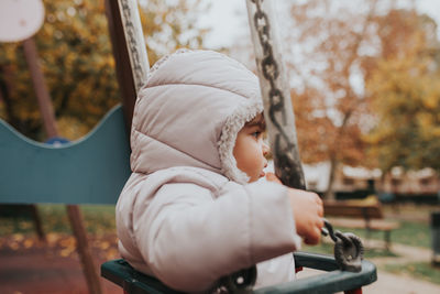 Baby girl sitting on swing at playground