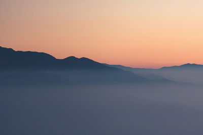 Scenic view of silhouette mountains against clear sky during sunset