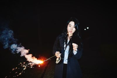 Portrait of woman holding sparklers at night