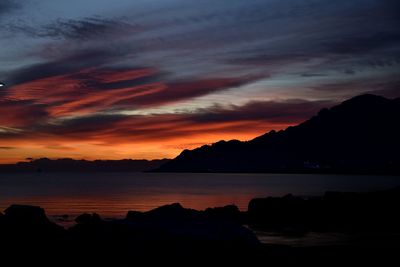 Scenic view of sea against dramatic sky during sunset