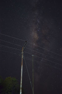 Low angle view of electricity pylon against sky at night