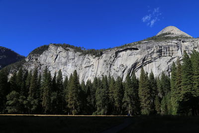 Low angle view of rocky mountains against clear blue sky