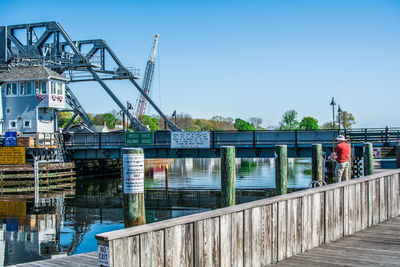 Cranes against bridge against clear sky