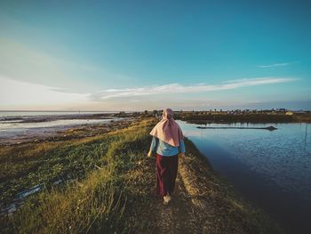 Rear view of man standing on beach against sky
