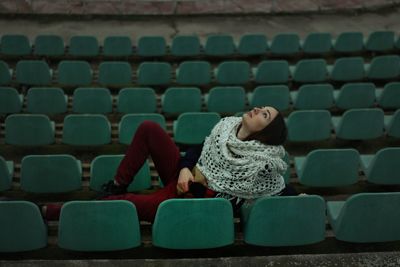 Woman reclining on chairs at stadium