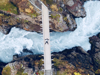 Directly above shot of man lying on footbridge over river