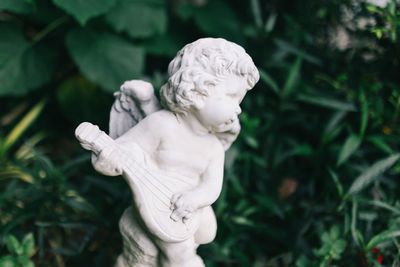 Close-up of angel statue against plants