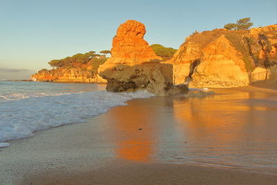 Rock formation on beach against clear sky