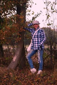 Portrait of smiling woman standing by tree on field