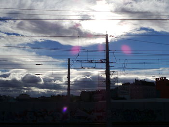 Low angle view of power lines against cloudy sky