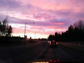 Cars on road against sky during sunset