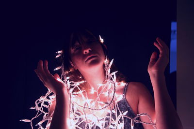 Teenage girl with illuminated string light in darkroom