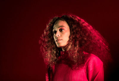 Portrait of young woman against red background