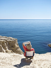 Spain, andalusia, cabo de gata, back view of woman with plastered arm looking at the sea